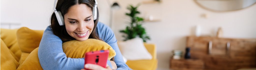 Junge Frau mit Kopfhörern am Smartphone. | Jeune femme avec des écouteurs utilisant un smartphone. | Young woman with headphones on her smartphone.