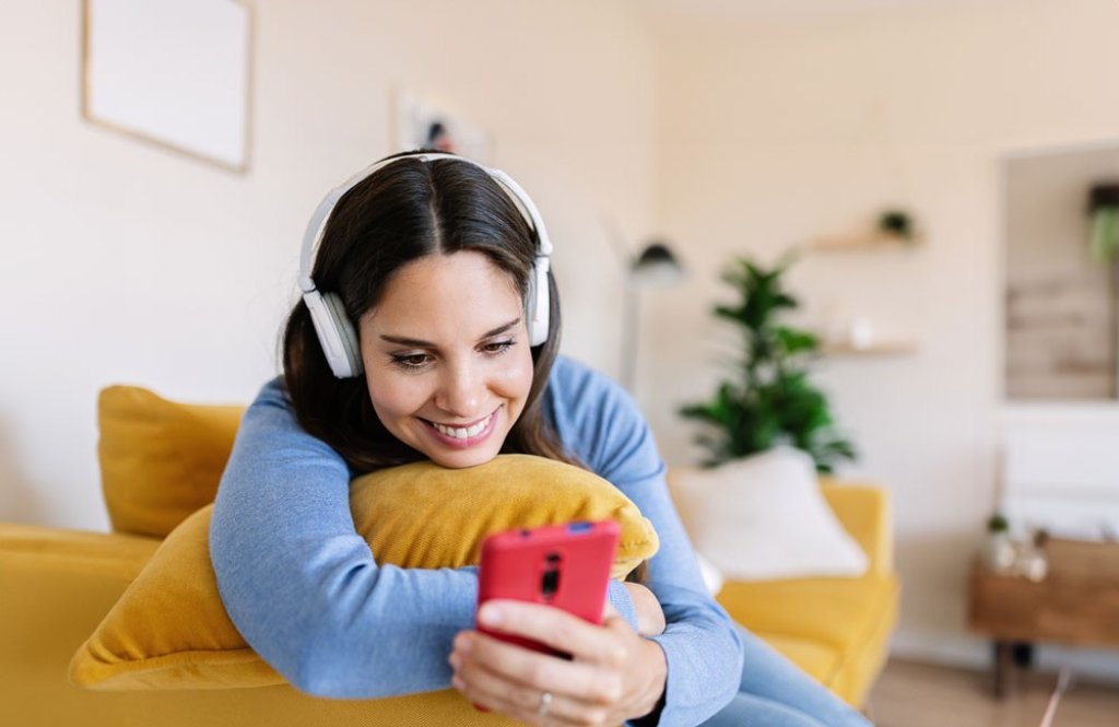 Junge Frau mit Kopfh&ouml;rern am Smartphone. | Jeune femme avec des &eacute;couteurs utilisant un smartphone. | Young woman with headphones on her smartphone.